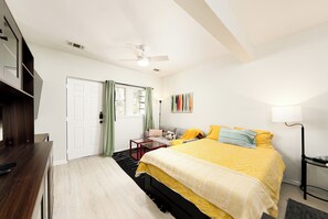 A bedroom with a bed, a desk, a chair, a lamp, and a ceiling fan. - 5 Min to Downtown - Huge Yard - Dog Friendly -3GB/s Wifi - 75" TV (Austin)