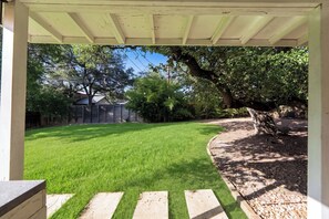 A backyard with a grassy lawn, a wooden deck, and a covered patio area. - 5 Min to Downtown - Huge Yard - Dog Friendly -3GB/s Wifi - 75" TV (Austin)