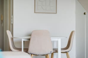 A dining area with a white table and two chairs with wooden legs. - GuestReady - Dream Corner (Caniço)