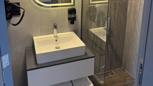 A modern bathroom with a vanity, a mirror, a shower, and a glass-enclosed shower area. - The Liora Hotel (Boyabat)