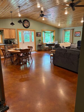 A spacious living area with a wooden floor, a dining table with chairs, a sofa, and a ceiling fan. - Welcome to Bud and Jacquie Sue’s (Sterling)