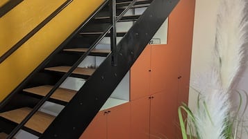 Un escalier avec une rampe en métal noir, des marches en bois et un mur jaune.