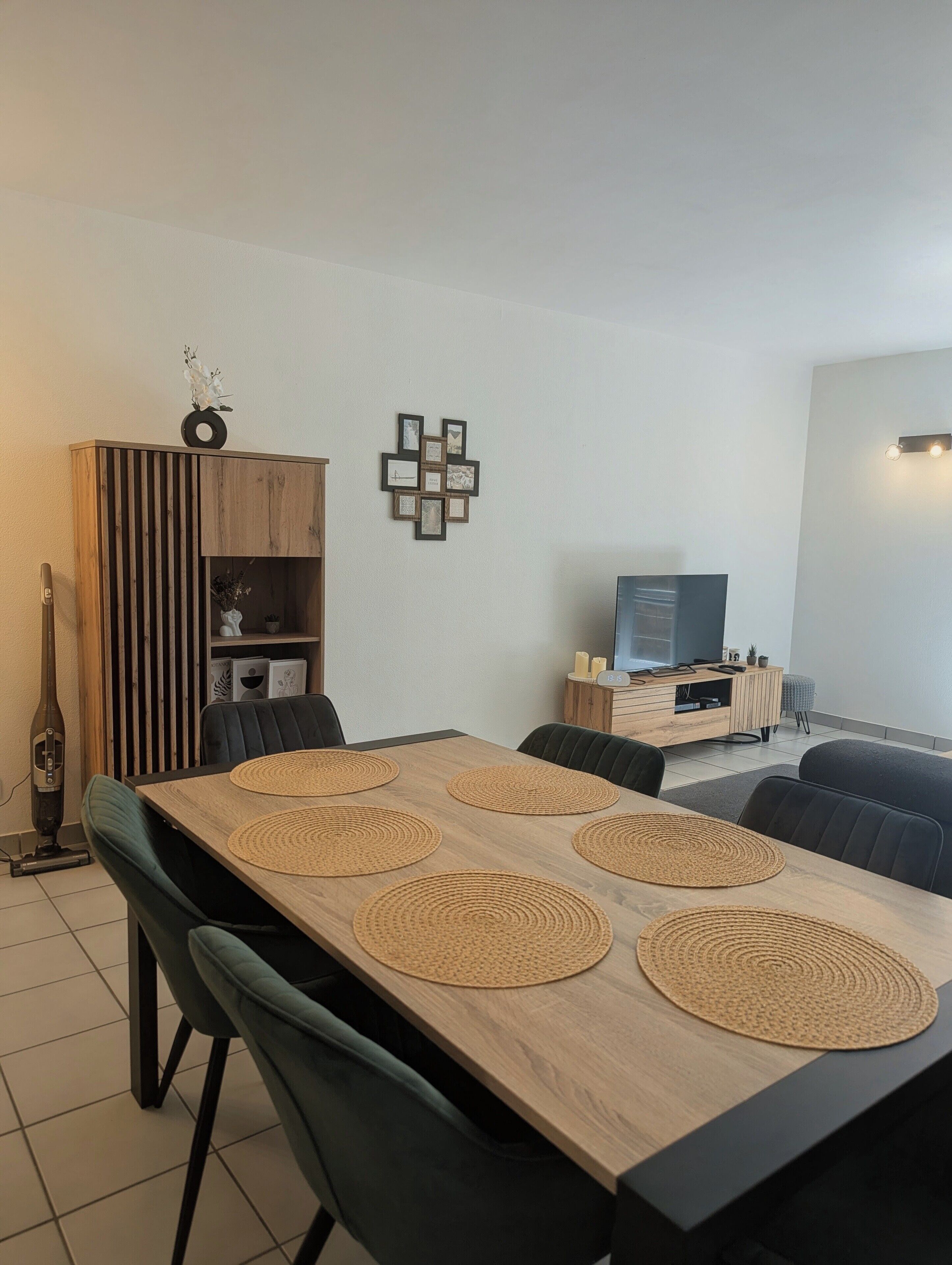Zona pranzo con tavolo in legno, sedie nere e sottopiatti intrecciati.