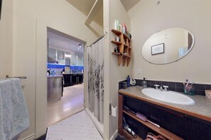 A bathroom with a sink, mirror, and shelves with toiletries. - Trendy suite in Mission! Steps away from 17th ave, the river and Stampede (Calgary)