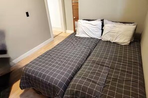 A bedroom with a bed, two pillows, and a wooden headboard. - Trendy suite in Mission! Steps away from 17th ave, the river and Stampede (Calgary)