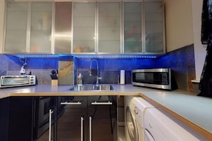 A compact kitchen with a built-in microwave, toaster, and washing machine. - Trendy suite in Mission! Steps away from 17th ave, the river and Stampede (Calgary)