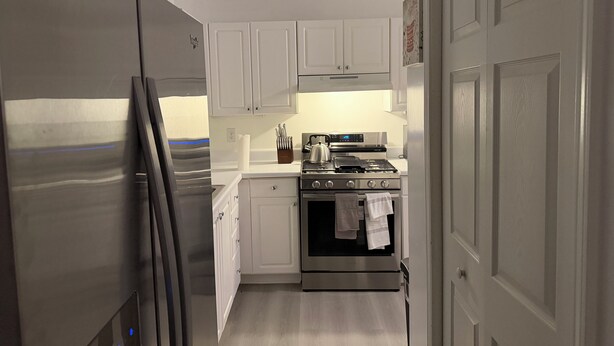 A compact kitchen with white cabinets, a stainless steel refrigerator, a stove, and a dishwasher. - 2 bedroom furnished townhome, washer & dryer, Central Air, Wifi & New appliances (Atlanta)