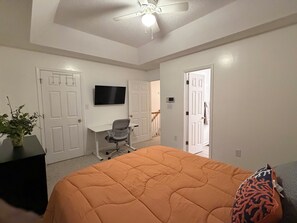A bedroom with a bed, a desk, a chair, and a television on the wall. - 2 bedroom furnished townhome, washer & dryer, Central Air, Wifi & New appliances (Atlanta)