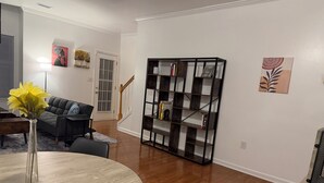 A living room with a round table, a sofa, a bookshelf, and a vase with flowers. - 2 bedroom furnished townhome, washer & dryer, Central Air, Wifi & New appliances (Atlanta)