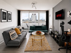A modern living room with a grey sofa, a green sofa, a coffee table, a TV, and a city view through the window. - Canary Wharf Apartment with Balcony, Workspace & Parking (London)