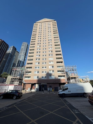 A tall residential building with multiple floors, a brick facade, and a flat roof. - Canary Wharf Apartment with Balcony, Workspace & Parking (London)