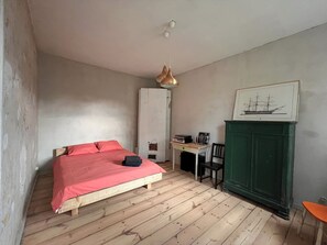 A room with a bed, a desk, a chair, a green cabinet, and a framed picture on the wall. - Historic 1885 Apartment near Liepāja center (Liepāja)