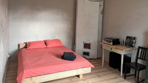 Et soveværelse med en seng, et skrivebord, en stol og en hængende lampe.