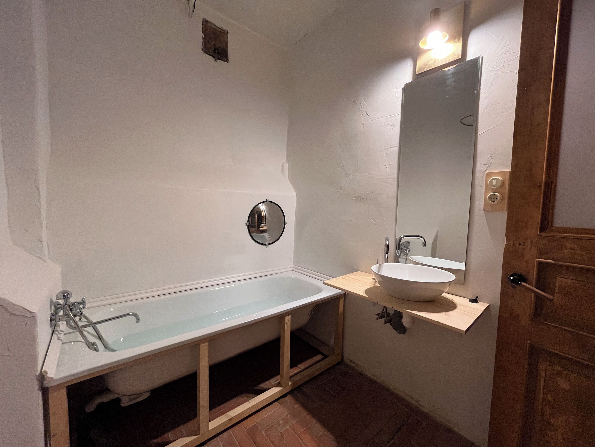 A bathroom with a bathtub, a sink, and a mirror.