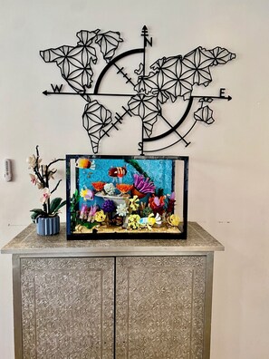 Eine dekorative Kompass-Wandskulptur über einem Schrank mit einem Aquarium.