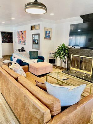 A modern living room with a sectional sofa, a glass coffee table, a fireplace, and artwork on the walls. - Cozy 1-bedroom house in peaceful Los Angeles with AC (Los Angeles)