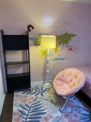 Ein Schlafzimmer mit einem Bett, einem Sessel, einer Lampe, einer Karte an der Wand und einer Leiter.