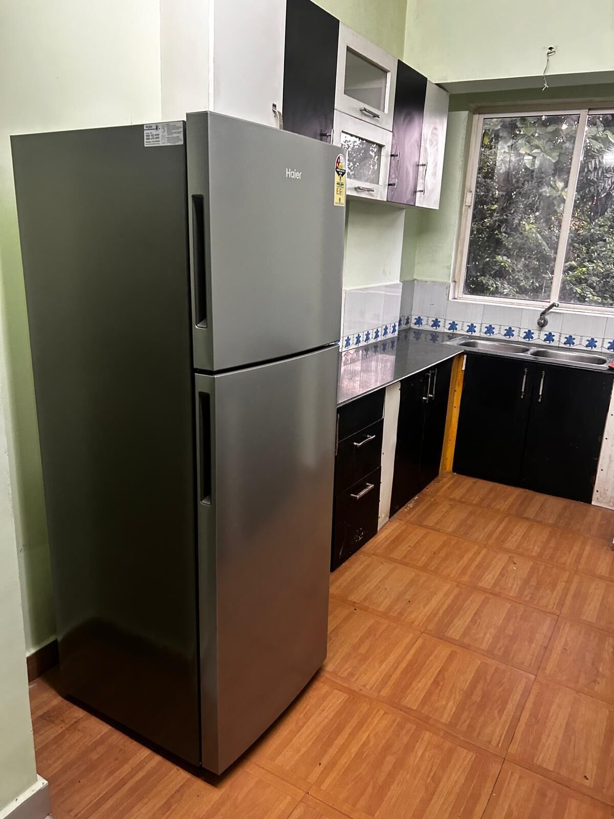 Eine kompakte Küche mit einem Edelstahl-Kühlschrank, einer Mikrowelle und einem Spülbecken.