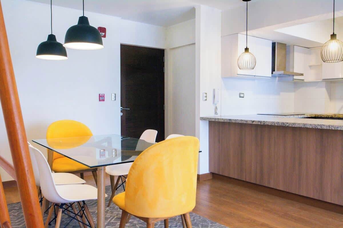 A modern kitchen with a wooden countertop and hanging pendant lights.