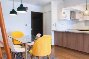 A modern kitchen with a wooden countertop and hanging pendant lights. - 3 APTS in One Building · Ideal for Large Groups! (Miraflores)
