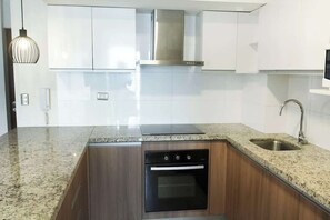 A modern kitchen with white cabinets, a stainless steel range hood, a built-in oven, and a granite countertop. - 3 APTS in One Building · Ideal for Large Groups! (Miraflores)