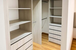 Een inloopkast met openslaande deuren, met meerdere planken en lades.