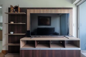 A modern entertainment unit with a flat-screen TV, wooden shelves, and a speaker. - 3 APTS in One Building · Ideal for Large Groups! (Miraflores)