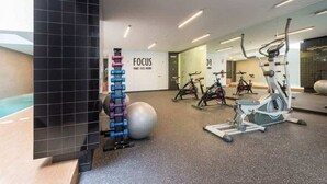 Ett modernt gym med olika träningsredskap, en stor spegel och en inspirerande vägg med ordet ”FOKUS”.
