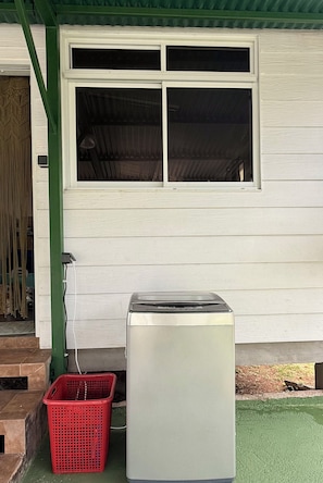 A white building with a window and a small appliance, possibly a refrigerator, next to a red plastic basket. - KOE HOUSE RAIATEA - FARE MATAHERE - View of Bora Bora & Sunsets (Tevaitoa)