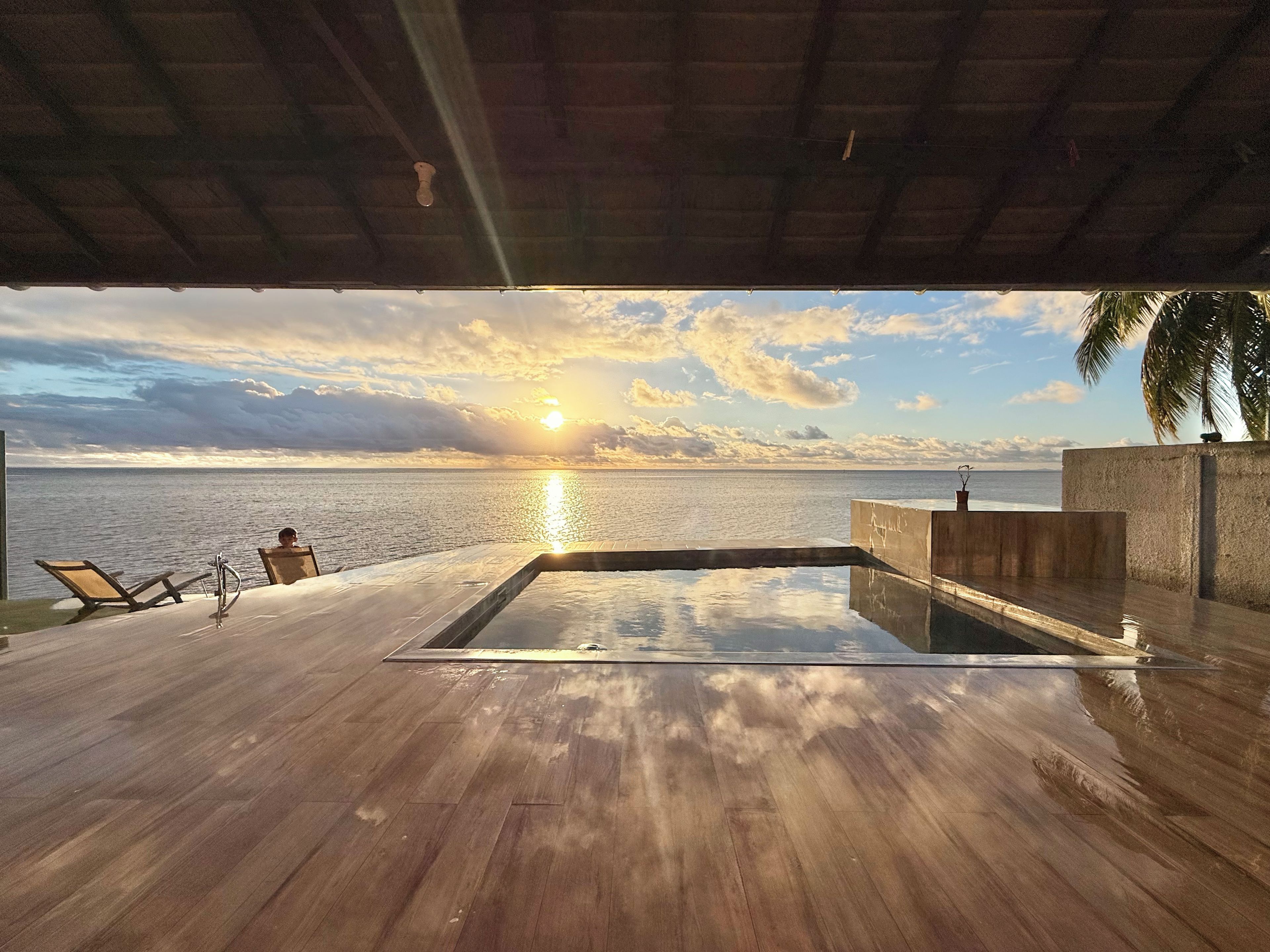Une piscine à débordement offrant une vue sur l’océan et le coucher de soleil.