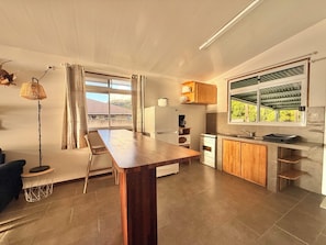 A modern kitchen with a dining area, large windows, and a view of the outside. - KOE HOUSE RAIATEA - FARE MATAHERE - View of Bora Bora & Sunsets (Tevaitoa)