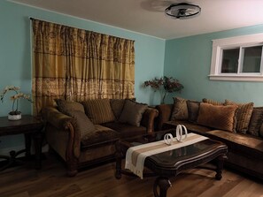 Una sala de estar con sofá, una mesa de centro y una ventana con cortinas.