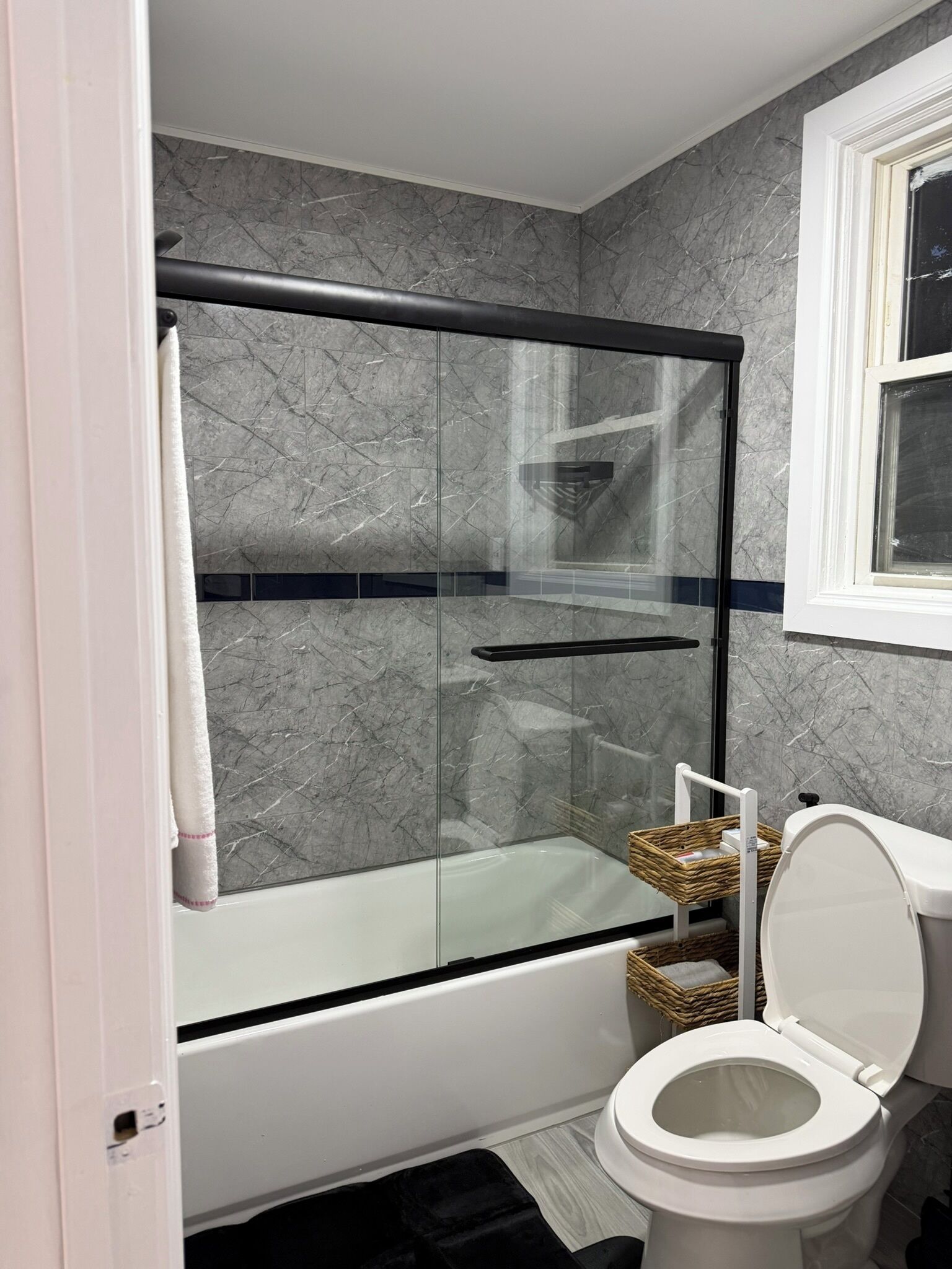 A bathroom with a glass-enclosed shower, a white bathtub, and a toilet.