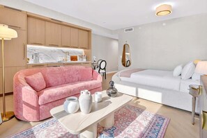 Ein modernes Schlafzimmer mit einem Bett, einem rosa Sofa, einem weißen Sofa, einem Nachttisch, einem Spiegel und einem Fenster.
