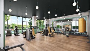 Un gimnasio moderno con diversos equipos de ejercicio, ventanas amplias y suelo de madera.