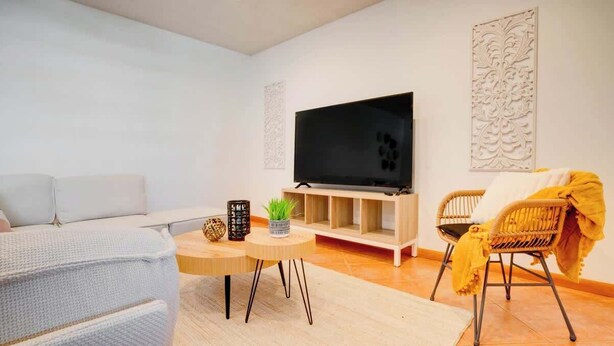 A modern living room with a flat-screen TV, a sofa, a chair, and a small table with decorative items. - 2BR Condo w/ Pool, BBQ, Parking | Beach & Galleria (Fort Lauderdale)