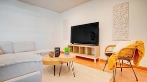 A modern living room with a flat-screen TV, a sofa, a chair, and a small table with decorative items. - 2BR Condo w/ Pool, BBQ, Parking | Beach & Galleria (Fort Lauderdale)