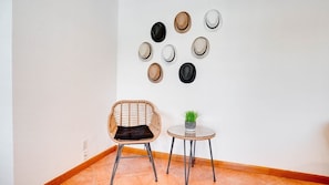 A room with a wicker chair, a small round table with a potted plant, and a wall with several circular wall decorations. - 2BR Condo w/ Pool, BBQ, Parking | Beach & Galleria (Fort Lauderdale)