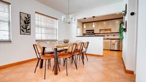 Eine moderne Küche mit Holzausbau, einer zentralen Kochinsel und einem Essbereich mit rundem Tisch und Stühlen.