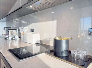 Eine moderne Küche mit integriertem Induktionskochfeld, einer Kaffeemaschine und einem dekorativen Behälter.