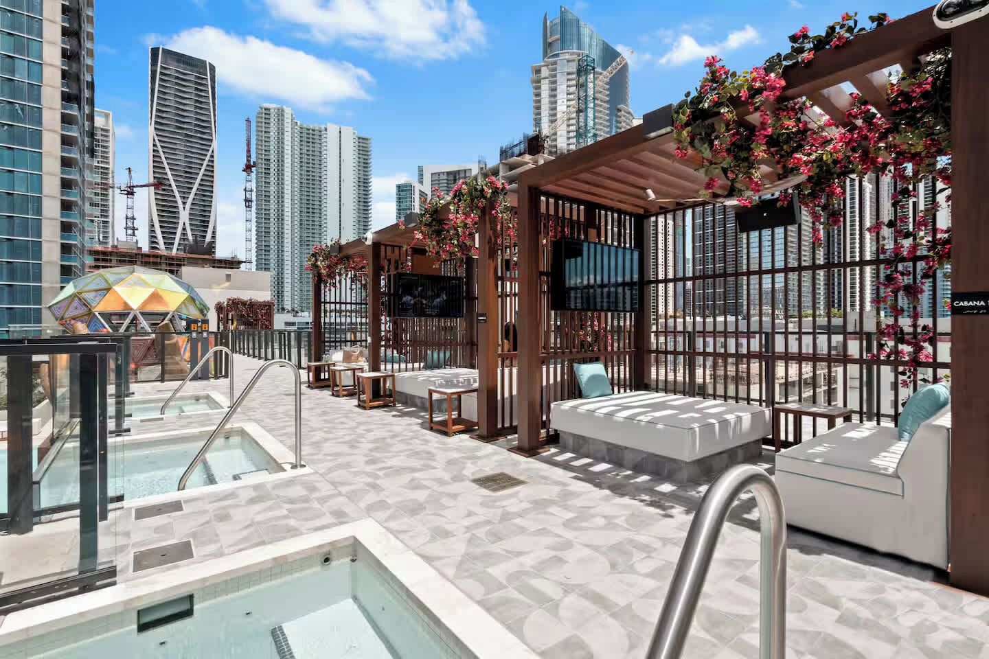 Un salon sur le toit avec une piscine, des espaces de détente et une vue panoramique sur la ville.