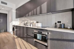 A modern kitchen with stainless steel appliances, a built-in oven, and a large island with a sink. - Luxury Studio | Prime Downtown Views (Miami)