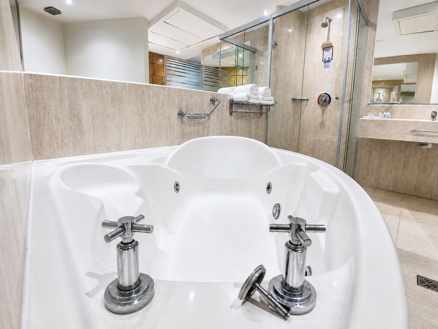 Een moderne badkamer met een groot wit bad, een douchecabine met glazen wanden en een wastafel met spiegel.