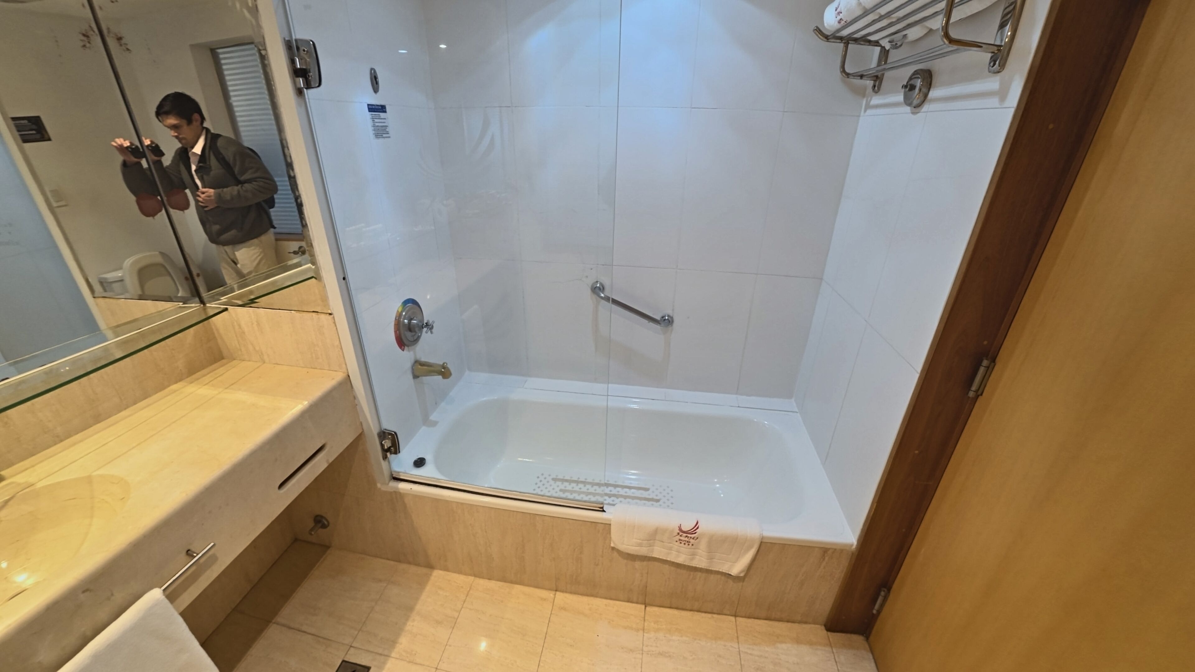 A modern bathroom with a glass-enclosed shower, a bathtub, and a vanity with a towel.