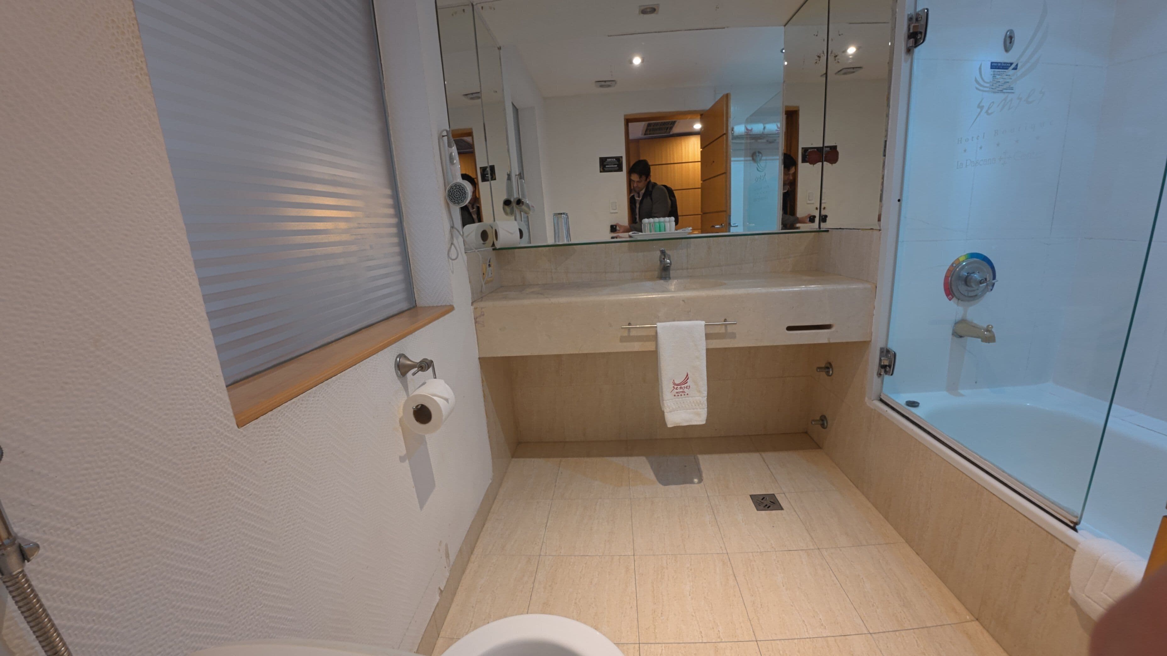 A modern bathroom with a glass shower enclosure, a toilet, and a sink with a towel hanging on the wall.