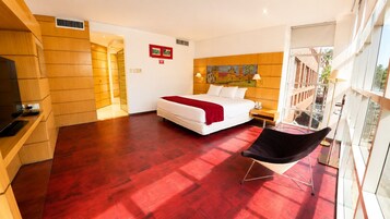 Una habitación de hotel con una cama, una silla, un cuadro en la pared y vistas por la ventana.