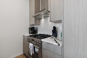 A modern kitchen with a stainless steel stove, a coffee maker, and a knife block. - Stunning water view, pet friendly, luxury 3-bedroom townhome with AC in Seattle (Seattle)
