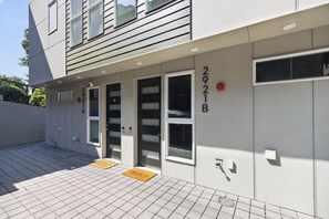 A building with a modern design, featuring a set of double doors, a fire alarm, and a 'HELLO' mat at the entrance. - Stunning water view, pet friendly, luxury 3-bedroom townhome with AC in Seattle (Seattle)