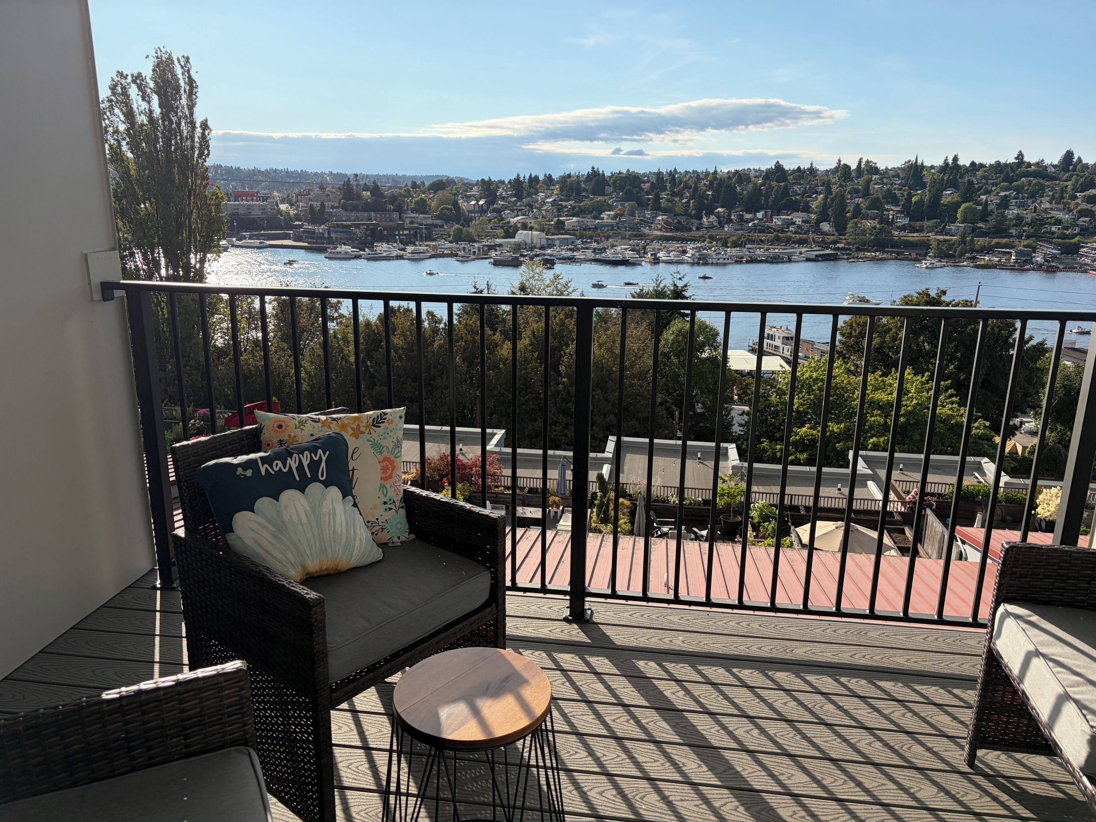 A balcony with wicker furniture, a view of a marina, and a cityscape in the background.
