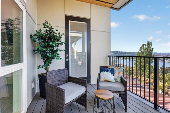 A balcony with wicker furniture, a potted plant, and a view of a body of water. - Stunning water view, pet friendly, luxury 3-bedroom townhome with AC in Seattle (Seattle)